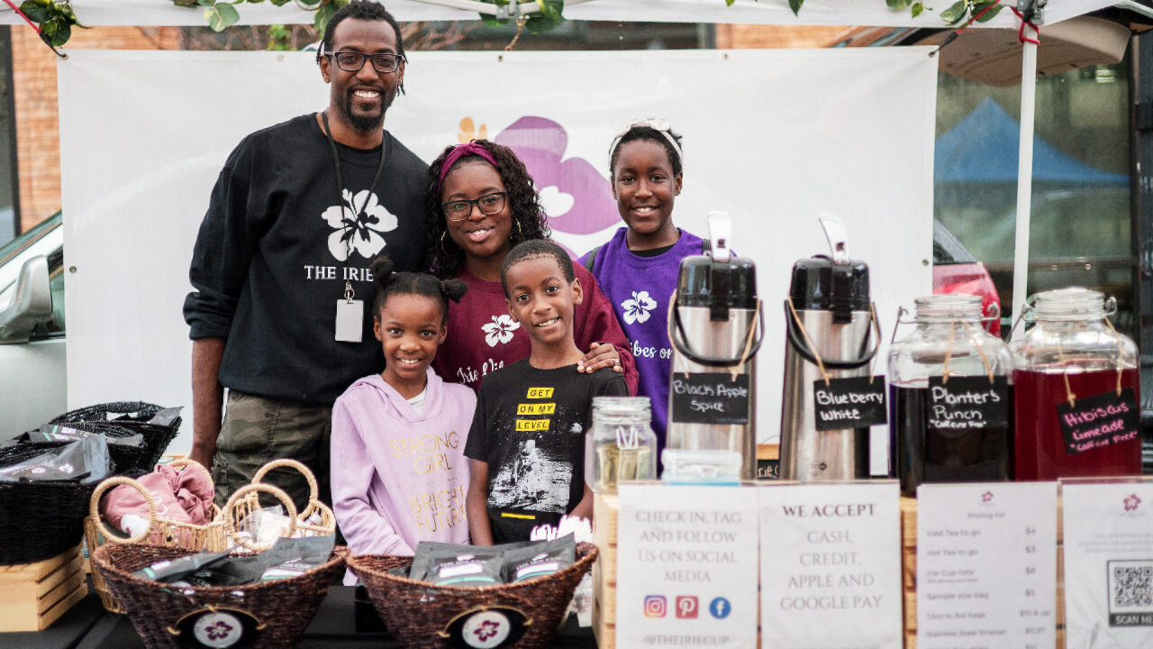 The Irie Cup founders Joseph and LaShanda Lewis with their kids at a local farmers market in Illinois selling their tea and branded merch